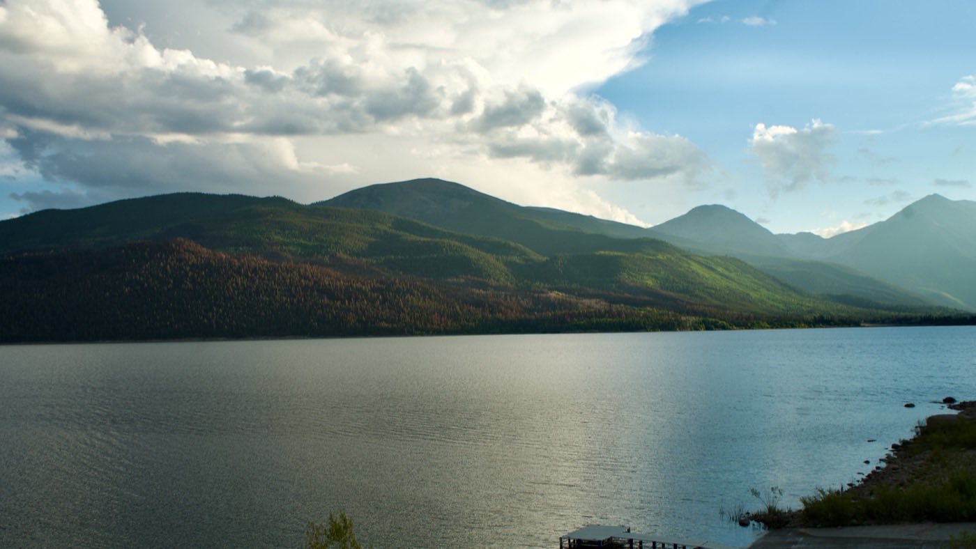 Late afternoon light over Twin Lakes, with forested ridges and a small dock at the shore.